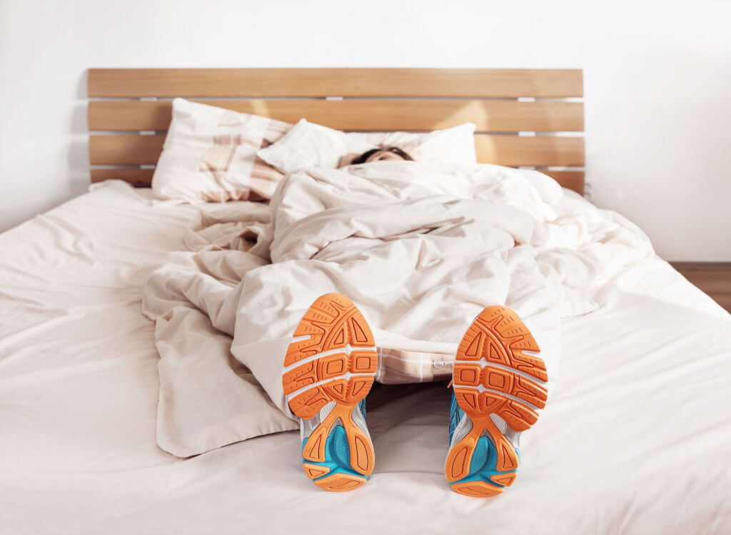 Спящая девушка в кроссовках на кровати